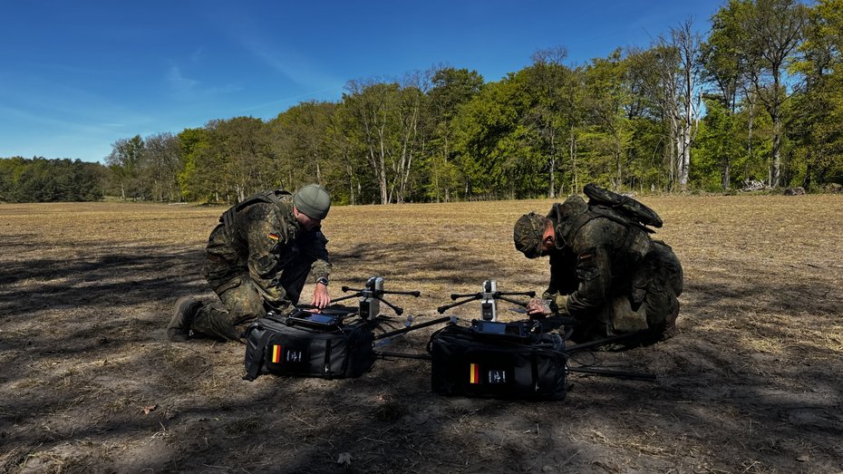 Zwei Einsatzkräfte bereiten AERIS Recon S1 Drohnensysteme mit mobilen Transporttaschen im Gelände für den Einsatz vor.