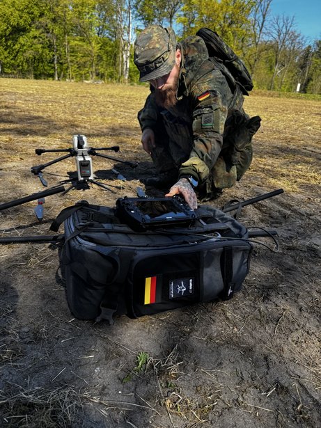 Einsatzkraft bereitet AERIS Recon S7 mit mobiler Transporttasche und Ground Control Station im Gelände für den Einsatz vor.
